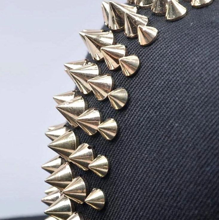 Detailansicht der Metallspitzen auf schwarzem Baumwollcanvas, Makroaufnahme der industriellegeöffneten Spike-Verschönerung mit sichtbarem Twill-Gewebe-Muster