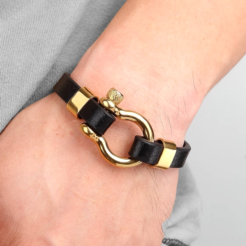 Mann trägt Gold-und-Schwarz Gothic-Toggle-Lederarmband am Handgelenk - casual Alltag-Alternative-Stil mit unisex Design