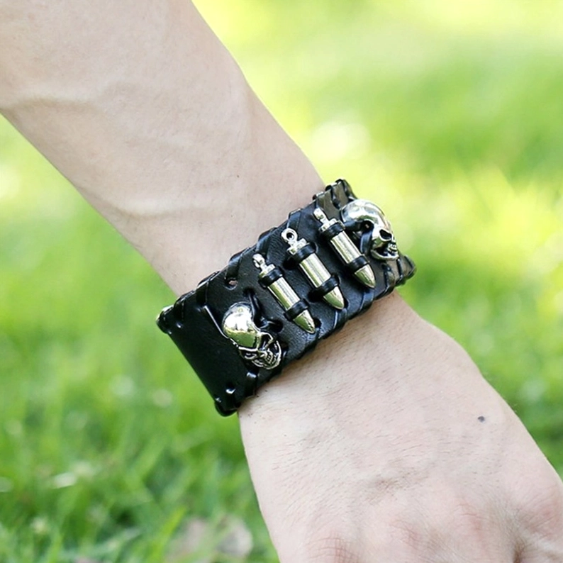Gothic Totenkopf Lederarmband am Handgelenk getragen im Freien, Nahaufnahme zeigt Punk-inspirierte Metallelemente und authentischen Trageeffekt im Tageslicht
