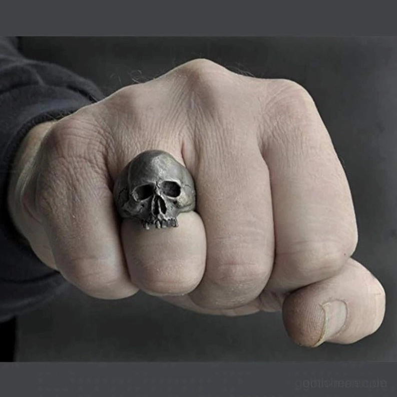 Dunkler gothic totenkopf bikerring an maennerlicher hand faustansicht zeigt kompakte bandform und verwittertes metall
