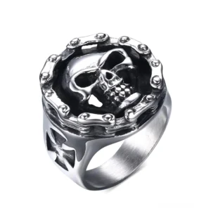 Gotischer Totenkopf-Kreuz-Ring aus Edelstahl mit Nieteneinfassung, Draufsicht zeigt detailliertes Knochenschädel-Relief und Kreuzausschnitt-Design, hochglanzpolierter Vintage-Silberton für Alternative-Mode und Bikerkultur