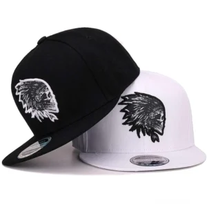 Gothic Totenkopf bestickte Snapback Kappe in schwarz und weiß Farbvarianten mit flacher Krempe, seitliche Ansicht zeigt die ikonische Schädel-Stickerei und strukturierte Konstruktion