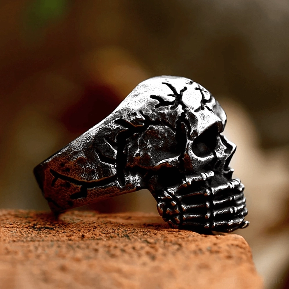 Gothic Edelstahl Totenschädel Ring Detailaufnahme zeigt knöcherne Finger Skelett-Kunstwerk und verwitterte knochenähnliche Oberfläche Textur