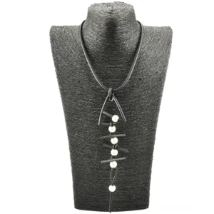 Dunkle gotische Fischknochen-Anhänger-Halskette auf strukturiertem schwarzem Schmuck-Display-Busten mit weißen Perlen-Details – alternative elegante Kette