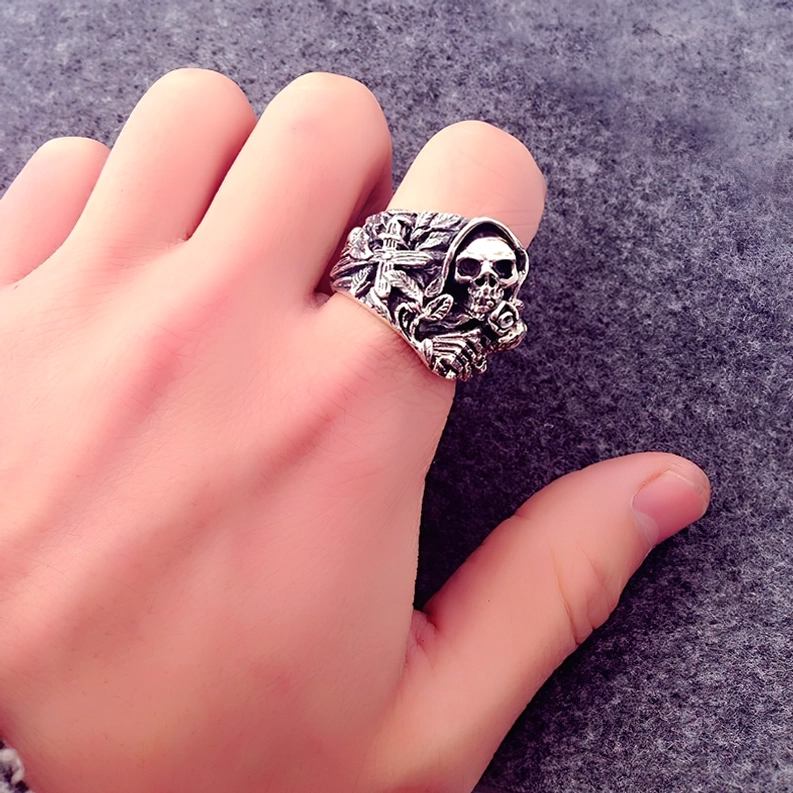925er Sterlingsilber gotischer Totenkopf Ring getragen an Hand über purpurnem Stoffhintergrund zeigt Vogelperspektive des Schädel- und Kreuzdesigns, tragbar und statement