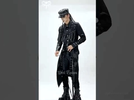 Männliches Modell in kompletter gotischer Punk-Tactical-Outfit einschließlich bestückter Jacke, Kappe, Layered-Strap-Rock und Platform Boots