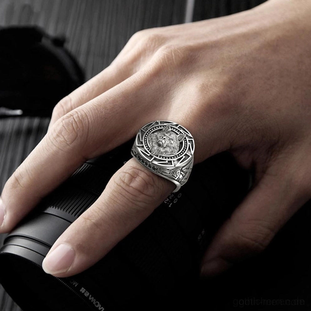 Gotischer Herren-Wolfsring am Zeigefinger einer Männerhand getragen, Seitenansicht, Vintage Silberfinish mit Kamera-Requisite als Hintergrund, Alltags-Styling