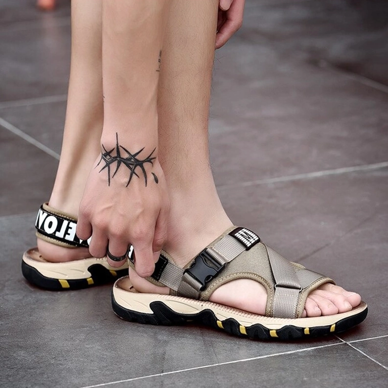 Männermodell trägt Khaki Gothic Sandalen mit sichtbarem fußtattoo, rückansicht zeigt verstellbaren fersenriemen mit schriftzeichendruck und sichere passform