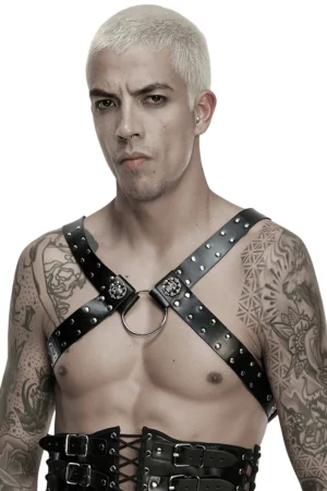 Bare-Chested Model mit schwarzem Studded-Kunstleder-Harness, zentrale Metallring-Details und abnehmbare Kettenketten, oberarmtattoos, Industrial-Gothic-Fashion-Statement