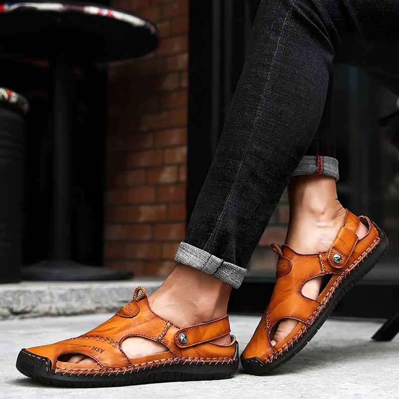 Mann im hochgerollten Denim trägt hellbraun Leder-Gothic-Sandalen mit handgenähtem Verschluss auf Pflasterweg – Dark Aesthetic Herren-Schuhwerk Street-Style