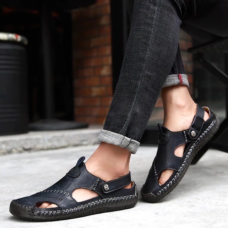 Mann trägt schwarze Leder-Gothic-Sandalen mit hochgerollter Jeans auf urbaner Straße, Lifestyle-Aufnahme im Tiefwinkel – Gotische Herren-Moccasins im alltäglichen Einsatz