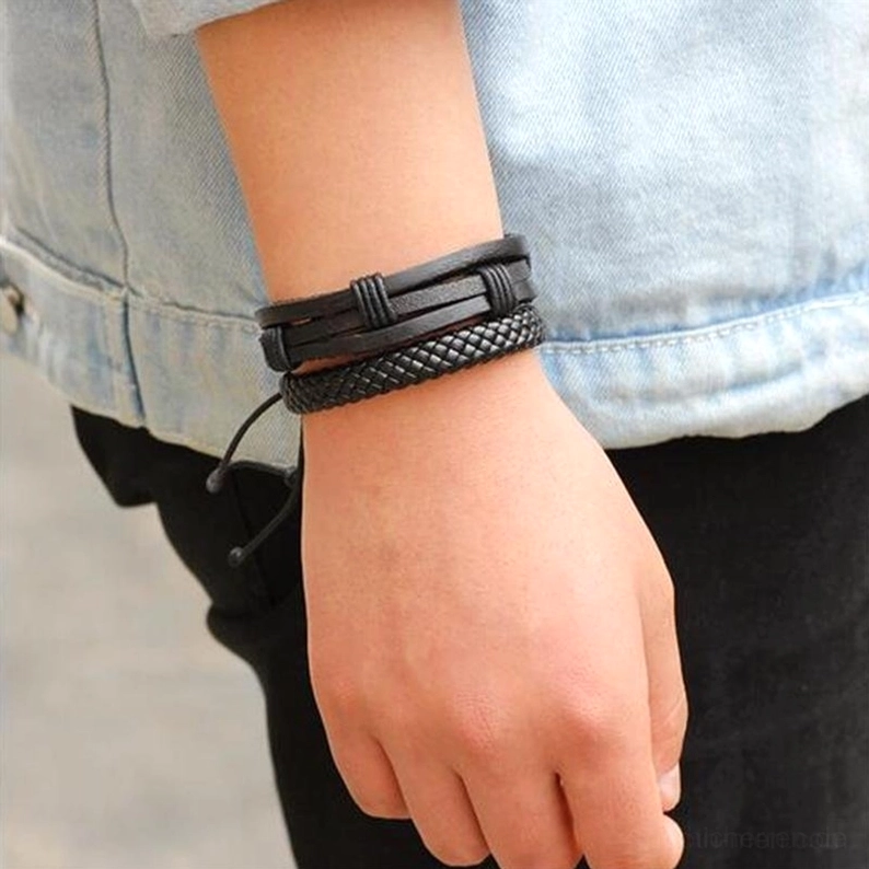 Mann trägt schwarzes geflochtenes Lederarmband am Handgelenk Seitenansicht Jeansjacke Gothic Armband Alltagsträgung