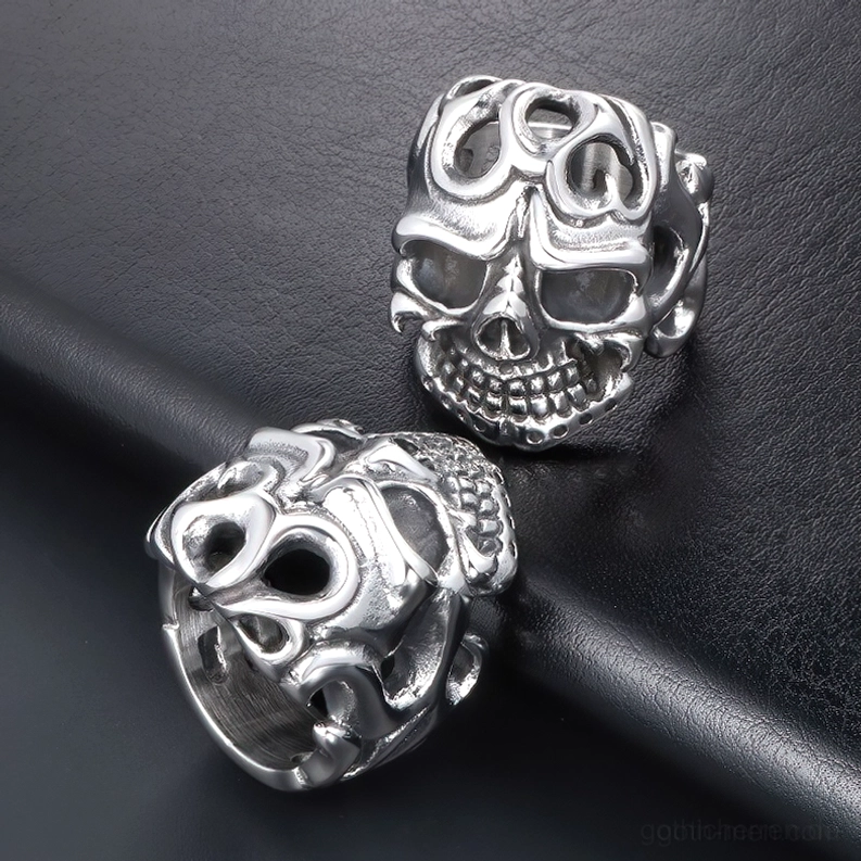 Zwei passende Edelstahl Totenkopfringe mit Vintage Tribal-Hohlschnitt-Design in Draufsicht auf schwarzer Lederfläche, Doppel-Set Gothic-Schmuck