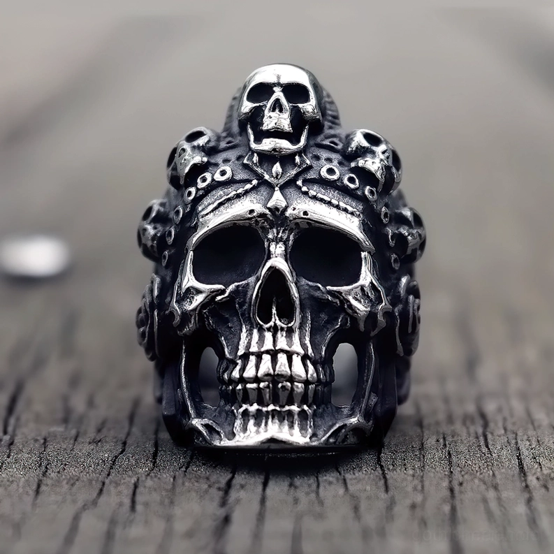 Matte dunkelsilber Totenkopf Biker Ring Frontansicht mit mehreren kleinen Totenkopfverzierungen auf Holzuntergrund