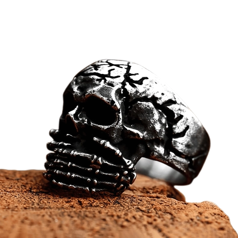 Gothic Totenschädel Siegelring Schrägansicht mit Patina-Details zeigt knöcherne Hände und antike Edelstahl-Oberfläche auf Holzuntergrund