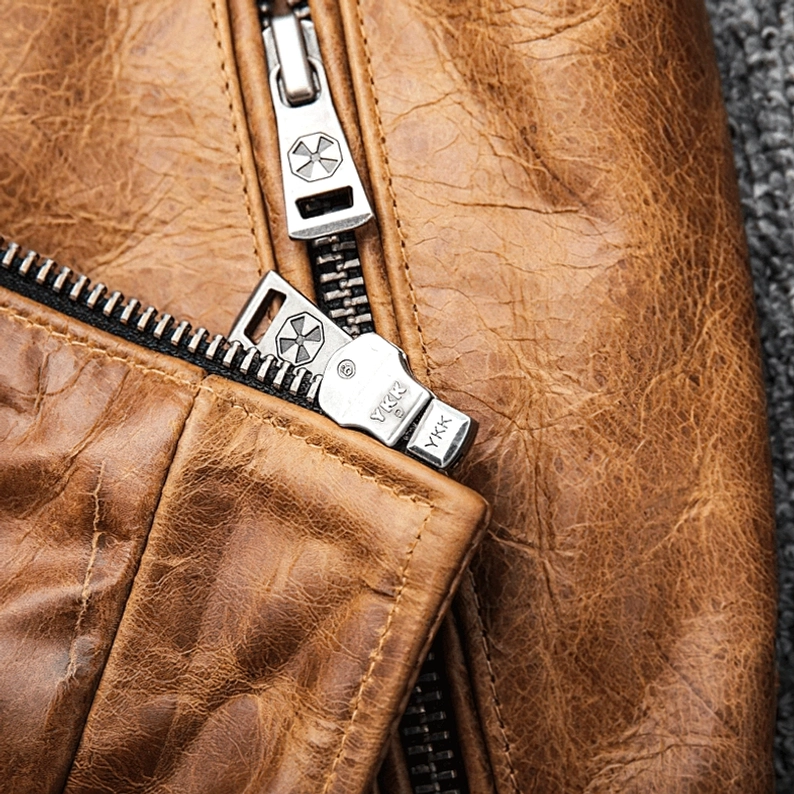 Großaufnahme des robusten silbernen Reißverschlusses und der distressed Camel Leder Textur auf der authentischen gothic Motorradjacke