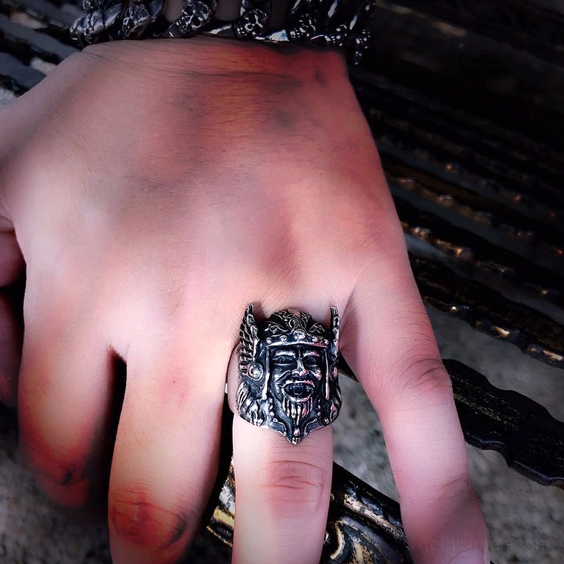 Odin Gothic Krieger Ring an männlichem Mittelfinger, Seitennahaufnahme gegen dunkle Metalloberfläche, vintage-silberner Edelstahl Siegelring-Stil, zeigt detaillierte Krieger-Gesicht und Helm auf Finger getragen