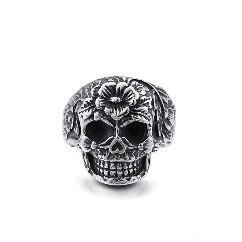 Ornater Totenkopf-Ring mit Blüten-Motiven aus Silber-Edelstahl, vordere Ansicht, geprägte Blumenmuster um die Schädelform, gotisches Memento-Mori-Schmuckstück, detaillierte Blüten- und Knochenlinien, Statement-Ring für Alternative-Fashion