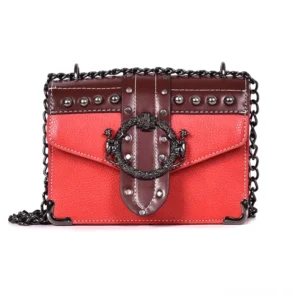 Rotbraune zweifarbige Gothic Schultertasche mit kontrastierenden Lederpanelen, silbernen Nieten-Details und robuster schwarzer Metallkettenkette, ornamentales Metallschloss, flache Produktaufnahme
