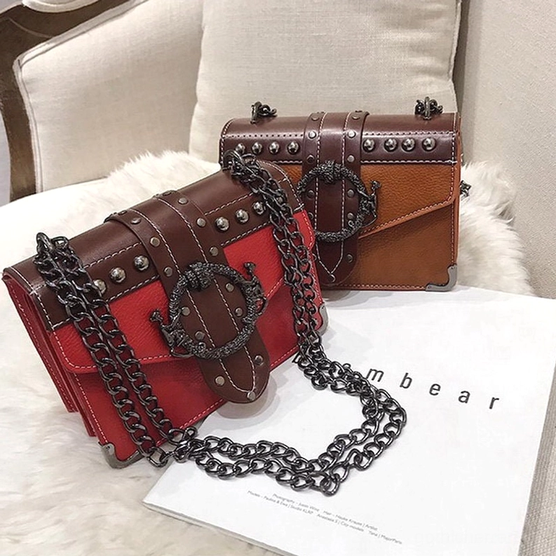 Rotbraune und Tan-Braune Gothic Schultertaschen auf flauschigem Hintergrund mit Modemagazin, Metallnieten-Embellishments und schwarze Kettenketten-Details, dunkle Gothic-Ästhetik-Styling