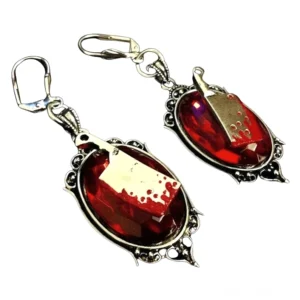 Rote blutige Fleischermesser-Gothic-Ohrringe mit goldfarbigem Fleischermesser und verziertem silbernem Filigree-Rahmen, karminrotes facettiertes Harz, Aufsicht auf weißem Hintergrund