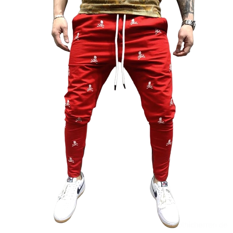 Rote All-Over-Totenkopf-bedruckte Gothic Lace-Up Röhrenhose für Herren, dunkle Ästhetik Skinny Pants mit roter Basis, weißem Skull-and-Crossbones-Print, Schnürweste und seitliche Reißverschlüsse an den Knöcheln
