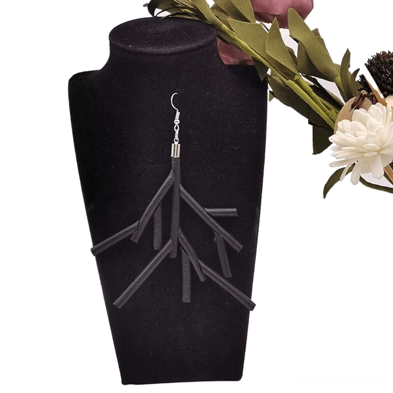 Schwarze Ast-Ohrringe auf schwarzem Samtständer mit floraler Studio-Kulisse präsentiert, romantische gotische Statement-Schmuck-Darstellung mit dekorativen Blüten