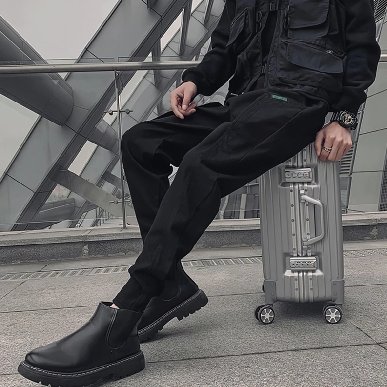 Schwarze Kordelzug-Cargo-Jogger mit Chelsea-Boots und Rollkoffer für modernes Reise-Styling