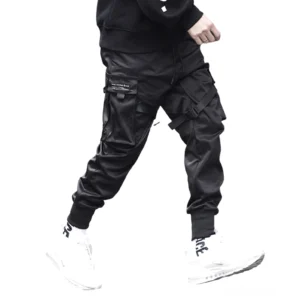 Schwarze Gothic Cargo Jogger mit Multi-Pocket Design, getragen von männlichem Model in Rückansicht, zeigt verjüngte Knöchelmanschetten und charakteristische Strap-Verzierungen der industrial techwear hose