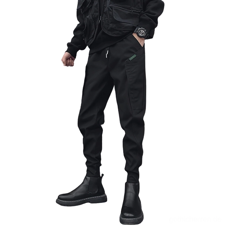 Schwarze Gothic Cargo-Jogger Vorderansicht mit Kordelzug-Bund und verjüngten Manschetten auf männlichem Modell mit Chelsea-Boots