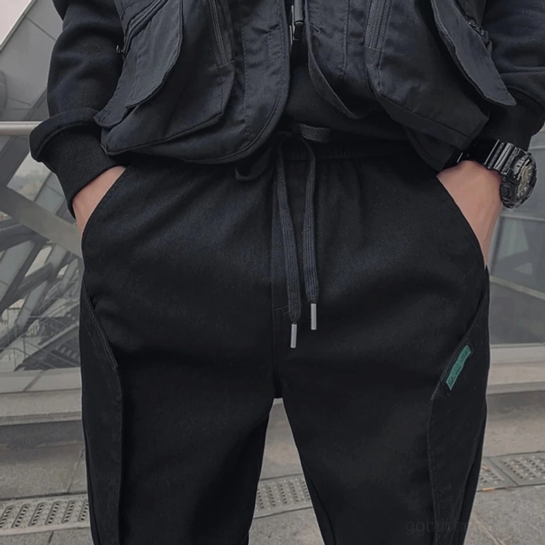 Nahaufnahme schwarze Cargo-Hose Taille und Taschenedetails mit Händen in den Taschen positioniert