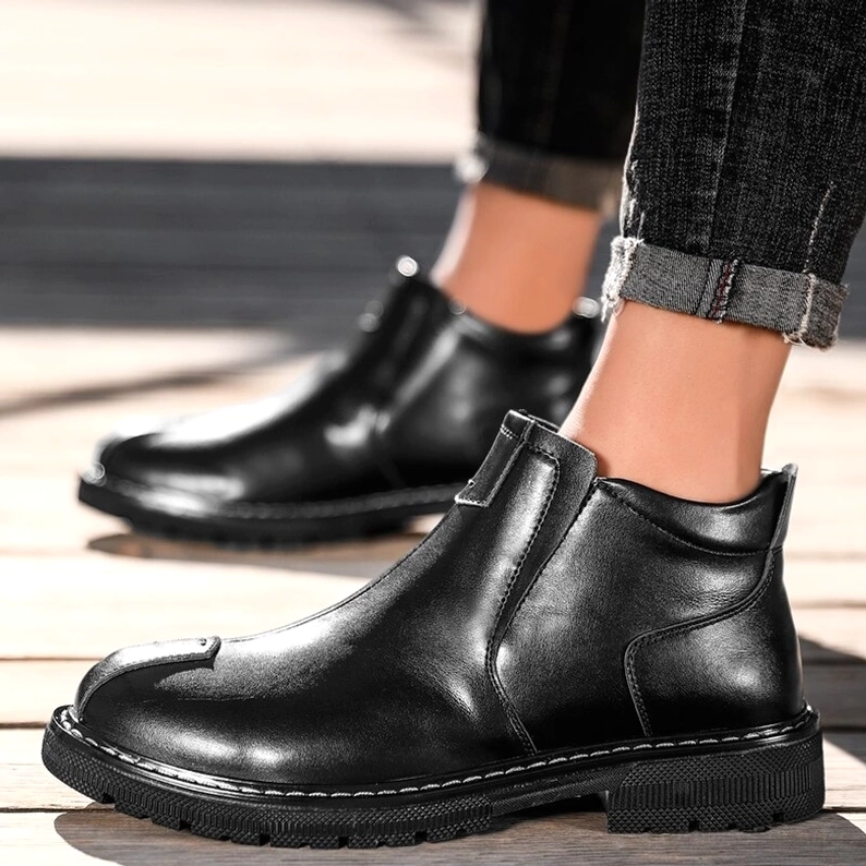 Gothic Knöchel-Stiefel für Herren in schwarzem Leder, getragen mit hochgekrempelten dunklen Jeans auf Holz-Außenhintergrund, Tragekomfort und Passform Demonstration
