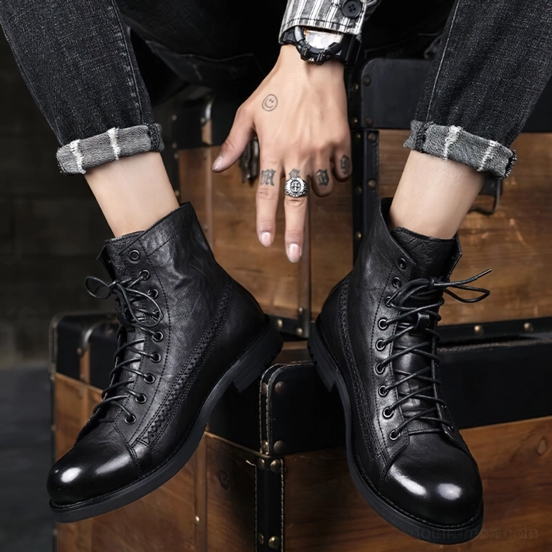 Herr trägt schwarze Gothic Combat Boots mit Vintage-Accessoires und hochgekrämpelten dunklen Jeans in Indoor-Studio