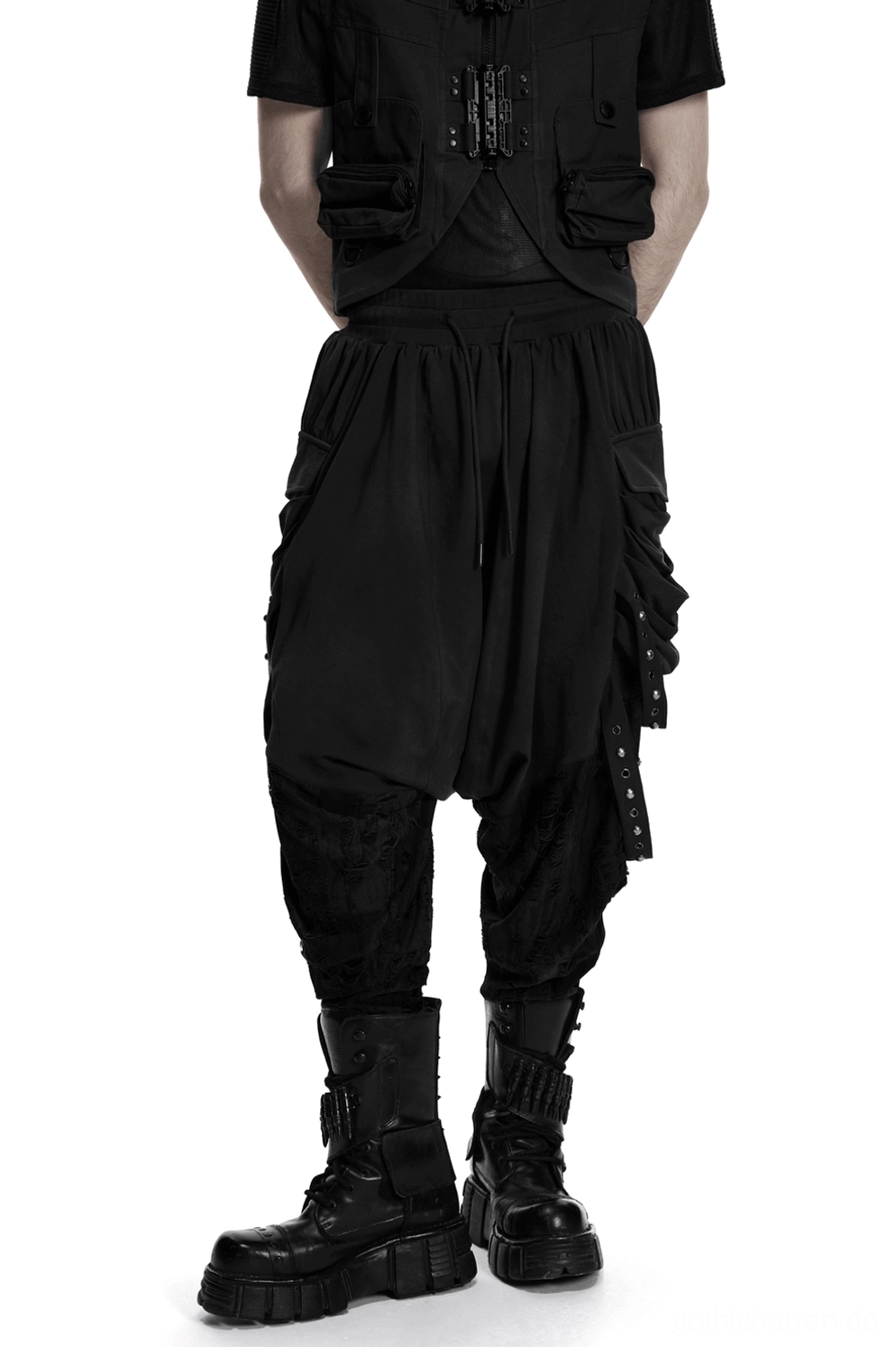 Schwarze Gothic-Haremshose mit Nieten-Cargo-Taschen, Vorderansicht-Dreiviertel-Blick auf männliches Modell mit Combat-Boots und industriellem Gothic-Stil