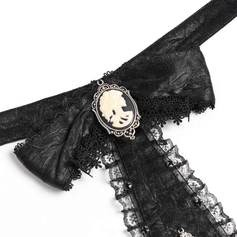Nahaufnahme detail der schwarzen gothic jabot krawatte mit kamee-porträt-brosche, gerüschter spitzeneinfassung und strukturiertem schwarzen stoff