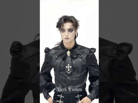 Männliches modell in voller torsoansicht mit schwarzer gothic jabot krawatte mit mehreren kreuzelementen und strukturierten schultern auf dunklem hintergrund