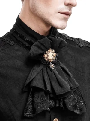 Nahaufnahme Detail der mehrschichtigen schwarzen Spitzen-Jabot mit feiner Stickerei am Saum und goldtoniertem Broschenverschluss am Modell