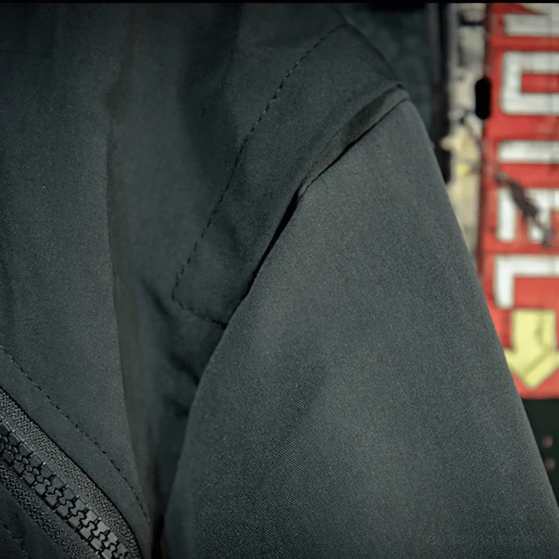 Schwarze Gothic Jacke Ärmel-Detail mit glatter Matter-Oberflächenmatte Polyester und Overlock-Nähte-Handwerk – Textur-Detailaufnahme professionelle Konstruktion