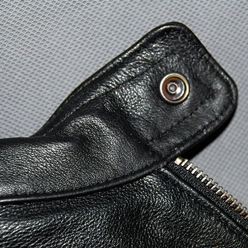 Echtes Leder Textur und Metall-Hardware Nahaufnahme Reißverschluss und Druckknopfverschlüsse schwarze Gothic-Bikerjacke