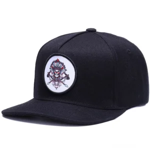 Schwarze Gothic Snapback Baseball Kappe mit besticktem indigenem Totenkopf-Motiv, Dreiviertelsicht vorne mit rundem Schädel-Abzeichen-Design
