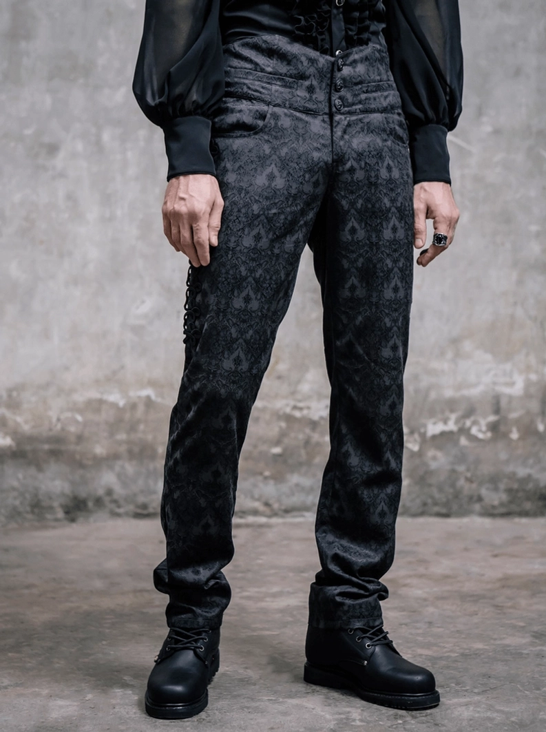 Schwarze Jacquard Gothic Steampunk Röhrenhose in vollständiger Frontansicht auf männlichem Modell mit hochgeschnittenem Schnitt, Kampfstiefeln und schwarzem Bishop-Sleeve-Hemd, industriales Umfeld