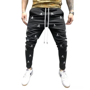 Schwarze Gothic Totenkopf Lace-Up Röhrenhose mit Schnürweste, von Herrenmodell in Frontalansicht vor Studio-Hintergrund getragen, zeigt das All-Over-Skull-Print-Design und die schwarze Basis mit weißem Totenkopf-Muster