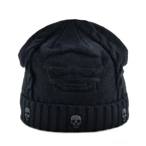 Schwarze gothic totenkopf strickmütze mit metallplakette von oben, zeigt gerippte krempe und zopfmuster-struktur aus vogelperspektive