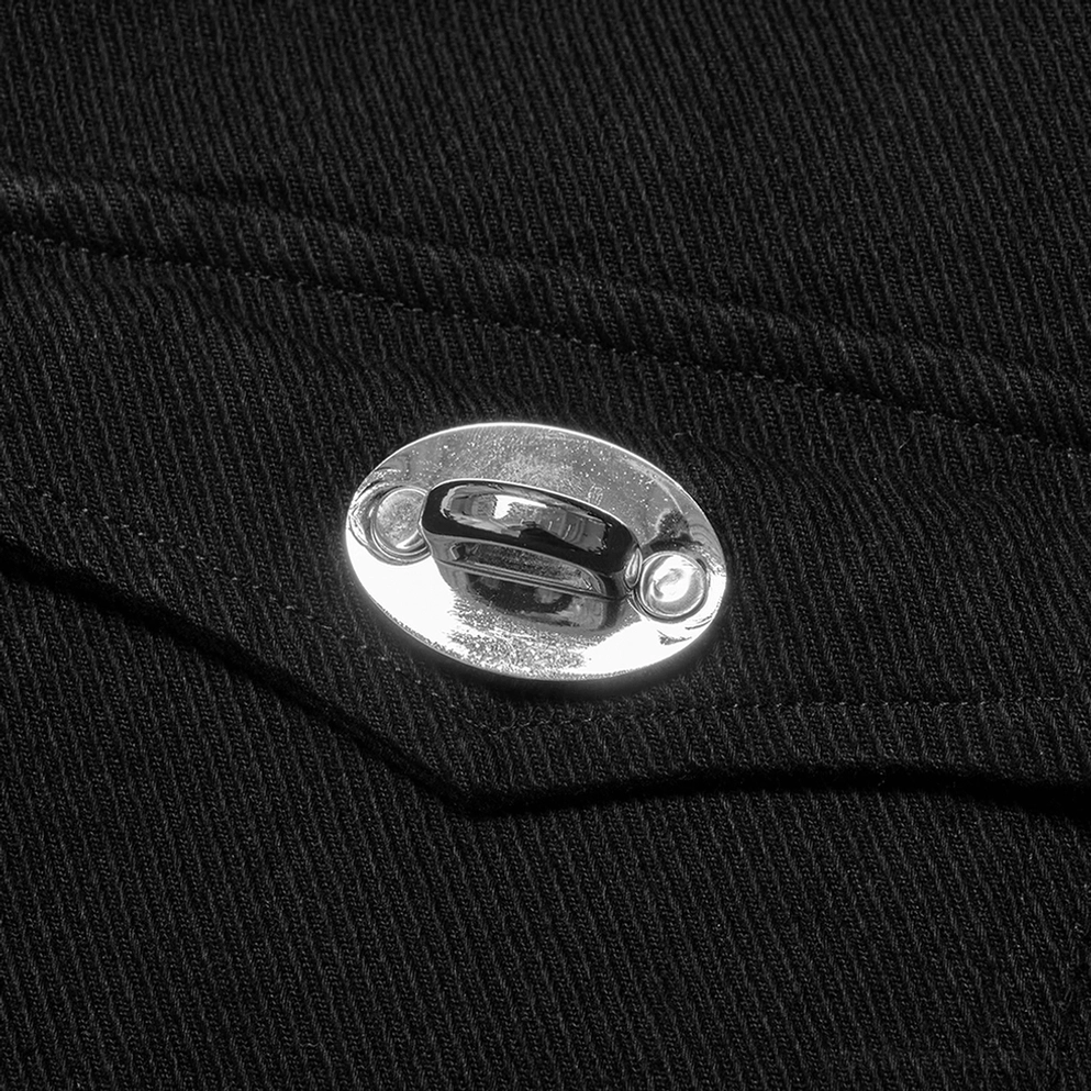 Makro-Detail des glänzenden silberfarbenen ovalen Metallknopf-Verschlusses auf schwarzem Twill-Stoff der Nieten-Weste, zeigend Verarbeitungsqualität
