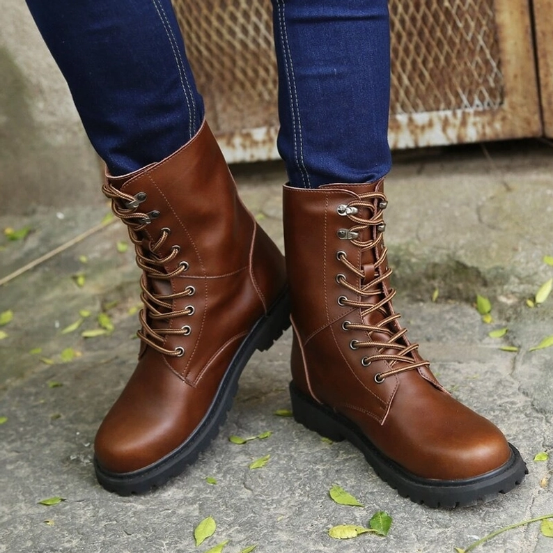 Schwarze hochschaftige gotische Kombatstiefel Vorder-Flachansicht, präzise Schnür-Konstruktion mit Stahlösen und elegante Silhouette hervorgehoben