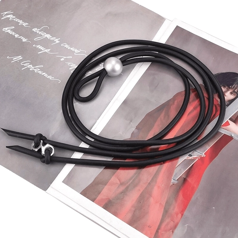 Abgewinkelte Flachlage der schwarzen Gummi-Gothic-Halskette mit Perle und Schraub-Metallakzenten – Produkt-Fotografie Detail auf Fashion-Magazin, professionelles Styling