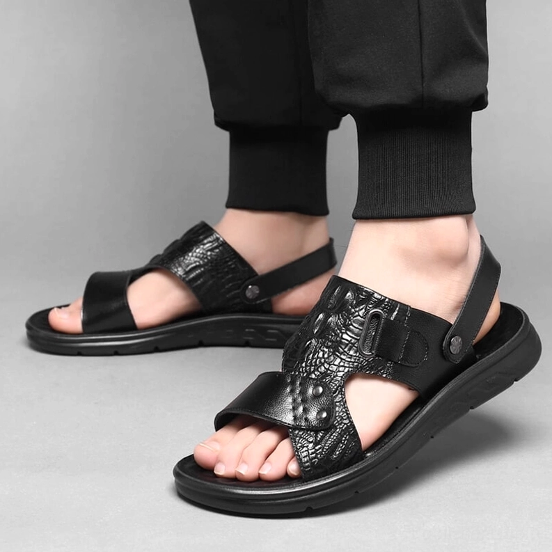 Schwarze Krokoreptil Ledersandalen getragen auf männlichem Modell mit schwarzer Cropped-Pants, Frontalansicht zeigt On-Foot-Styling und Tragekomfort