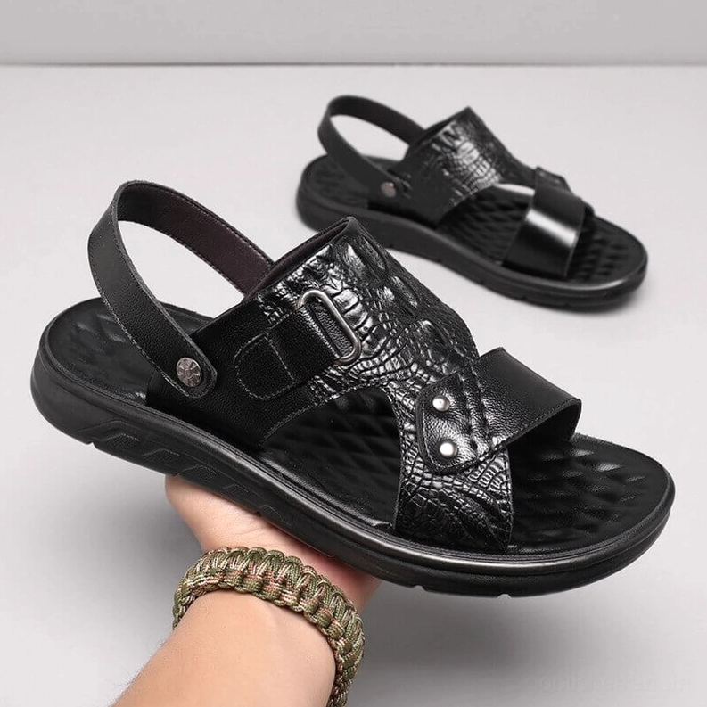 Schwarze Krokoprägung Ledersandalen in der Hand gehalten zeigt echte Ledertextur und Handwerk mit gotischem Stil und verstellbarer Schnalle