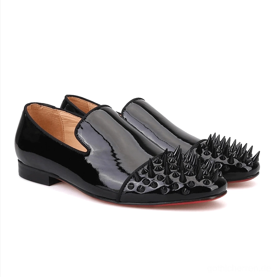 Paar schwarzer Lackleder Gothic Spike Loafer in Vorderansicht von schräg, hervorhebend die rote Gummisohle und geometrische Spike-Verzierungen