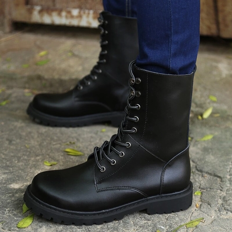 Schwarze matte Lederkombatstiefel, doppelte Seitenansicht mit Stahlhardware und strukturellen Stiefeldetails, Schnürung und Ösen klar erkennbar